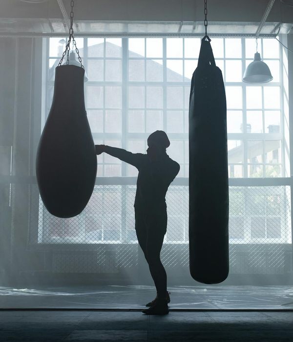 Man performing a strength exercise in a dark gym with aqua light accents.